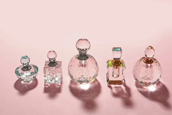 Diferentes botellas de perfume elegantes sobre fondo rosa — Foto de Stock