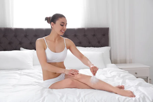 Жінка торкається ноги з пір'ям на ліжку вдома. Процедура вилучення — стокове фото