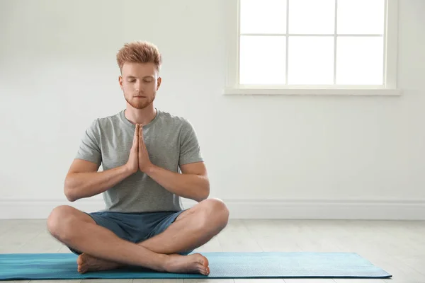 Joven guapo practicando yoga zen en interiores, espacio para el texto — Foto de Stock