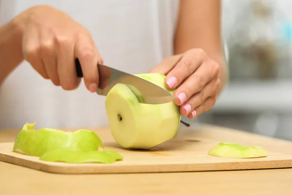 Mujer cortando manzana fresca en la mesa de madera en el interior, primer plano — Foto de Stock