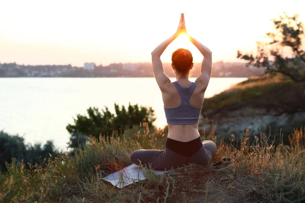 Молода жінка практикує йогу на свіжому повітрі на заході сонця. Дзен медитація — стокове фото