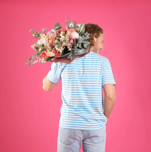 Homem segurando lindo buquê de flores no fundo rosa — Fotografia de Stock