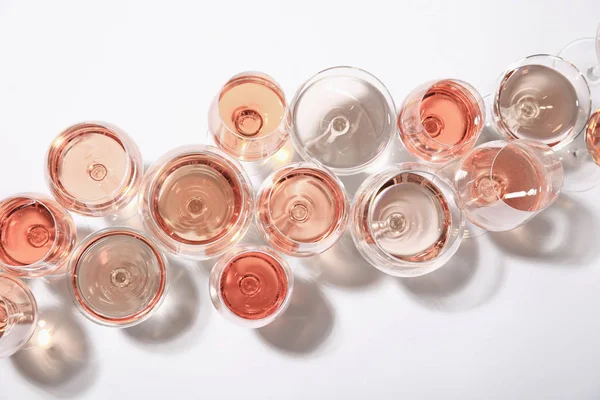 Diferentes copos com vinho rosa no fundo branco, vista superior — Fotografia de Stock