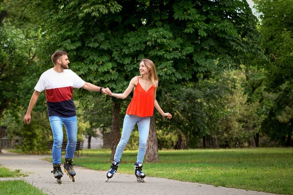 Jeune couple heureux patinage à roulettes dans le parc d'été — Photo