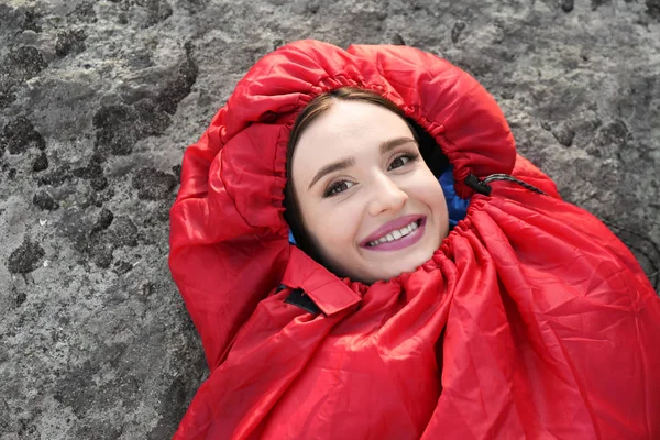 Junge Frau liegt in rotem Schlafsack im Freien — Stockfoto