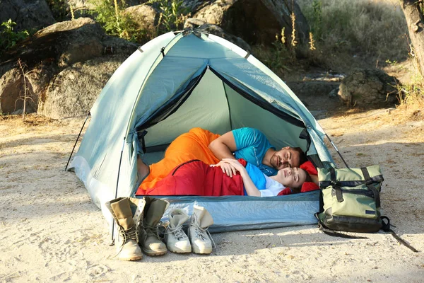 Молодая пара отдыхает в спальных мешках внутри палатки — стоковое фото