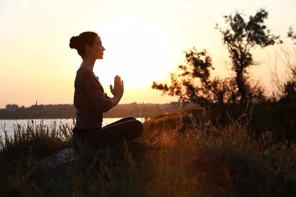 Mujer joven practicando yoga al aire libre al atardecer. Meditación zen — Foto de Stock