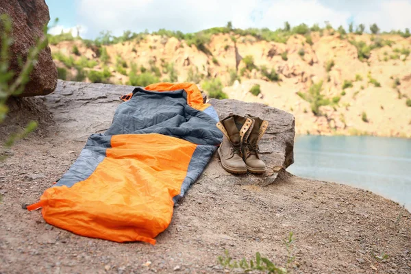 Schlafsack und Stiefel auf einer Klippe in der Nähe des Sees. Raum für Text — Stockfoto