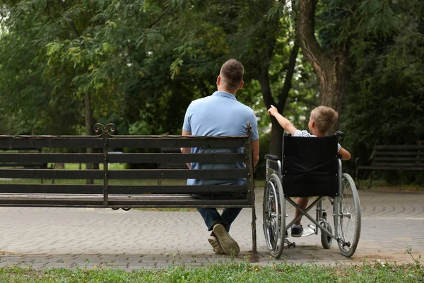 Pai com seu filho em cadeira de rodas no parque — Fotografia de Stock