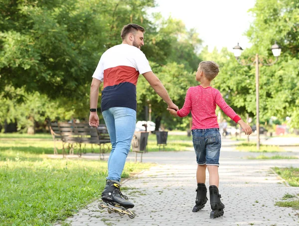 夏の公園で父と息子のローラースケート、バックビュー — ストック写真
