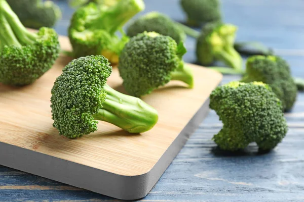 Papan dengan brokoli segar di meja kayu biru, closeup — Stok Foto