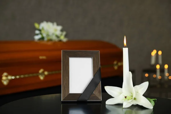 Moldura de foto preta com vela ardente e lírio branco na mesa na casa funerária — Fotografia de Stock