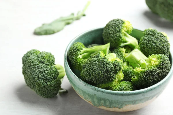 Skål och färsk broccoli på ljust grått bord, närbild — Stockfoto