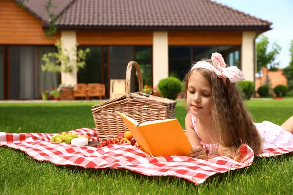 Gadis kecil yang lucu membaca buku di luar ruangan. Istirahat musim panas — Stok Foto