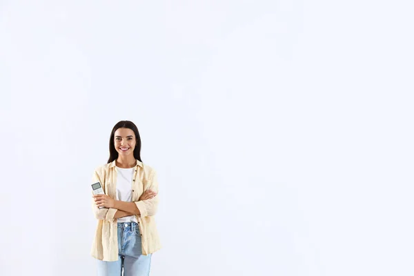 Ung kvinna med luftkonditionering fjärrkontroll på vit bakgrund — Stockfoto