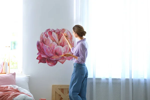 Młody projektant wnętrz malarstwo kwiat na ścianie w nowoczesnym pokoju — Zdjęcie stockowe