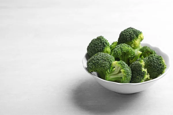 Bowl of fresh broccoli on light grey table, space for text — Stock Photo, Image
