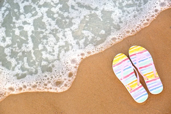 Des tongs élégantes sur le sable près de la mer, vue sur le dessus avec espace pour le texte. Accessoires de plage — Photo