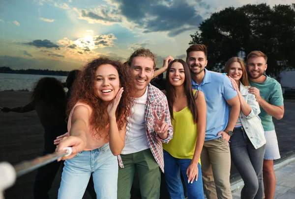 Jóvenes felices tomando selfie cerca del edificio de vidrio al atardecer —  Fotos de Stock