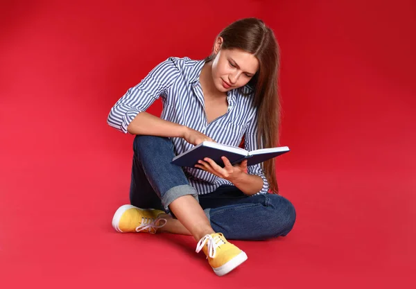 Belle jeune femme lecture livre sur fond rouge — Photo