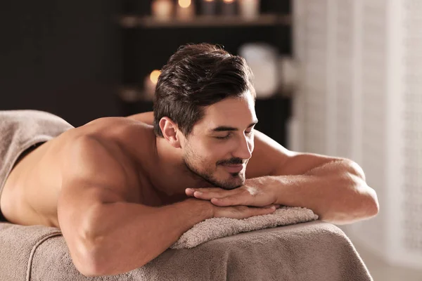 Красивий молодий чоловік розслабляється на масажному столі в спа-салоні — стокове фото