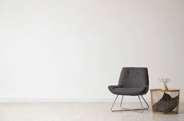 Стильный интерьер гостиной с удобным креслом и боковым столом рядом с белой стеной. Пространство для текста — стоковое фото