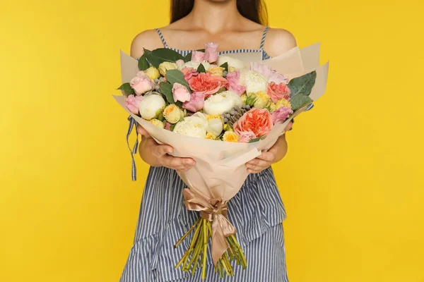 Ung kvinna som innehar vackra blombukett på gul bakgrund, närbild — Stockfoto