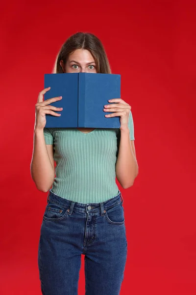 Schöne junge Frau mit Buch auf rotem Hintergrund. Lesezeit — Stockfoto