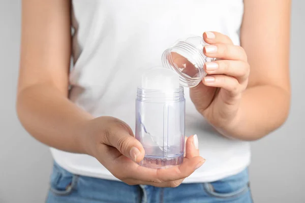 Mujer joven sosteniendo desodorante de palo de alumbre de cristal natural, primer plano —  Fotos de Stock