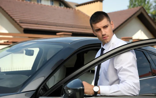 Attraente giovane uomo vicino auto di lusso all'aperto — Foto Stock