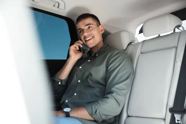 Привлекательный молодой человек разговаривает по телефону в роскошной машине — стоковое фото