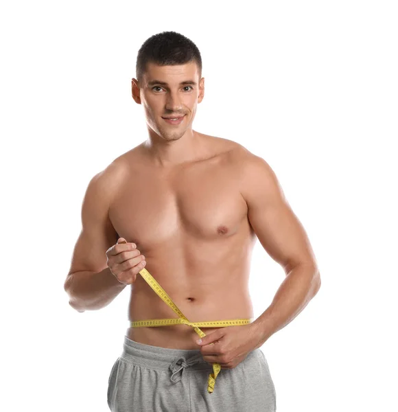 Mladý muž s štíhlým tělem používající měřicí pásku na bílém pozadí — Stock fotografie