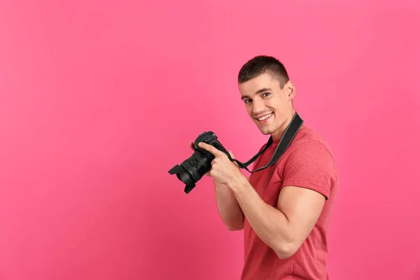 Young photographer with professional camera on pink background. Space for text — Stock Photo, Image