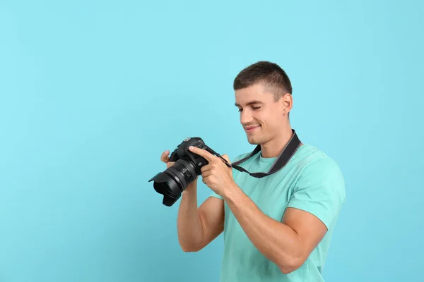 Ung fotograf med professionell kamera på ljusblå bakgrund. Utrymme för text — Stockfoto