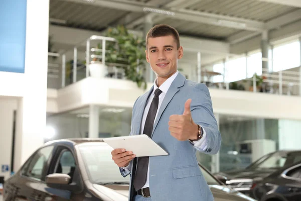 Jonge verkoper met Tablet in moderne autodealer — Stockfoto