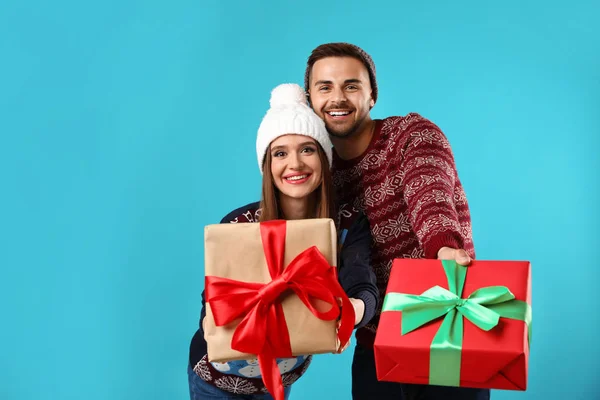 Casal em camisolas de Natal com caixas de presente no fundo azul — Fotografia de Stock