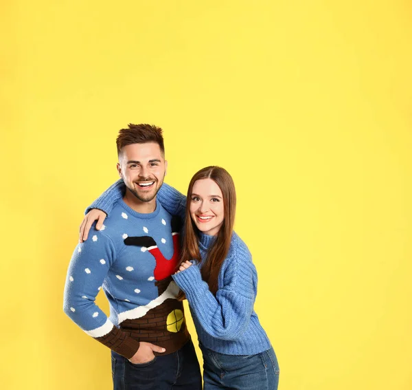 Pár viselő karácsonyi pulóverek, sárga háttér — Stock Fotó