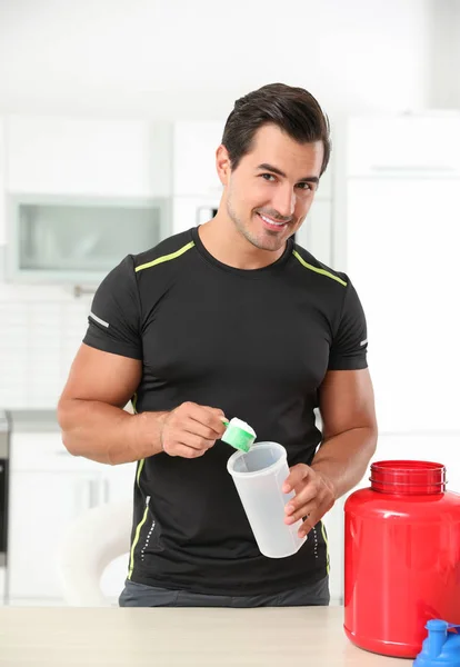 Jovem atlético homem preparando batido de proteína na cozinha — Fotografia de Stock