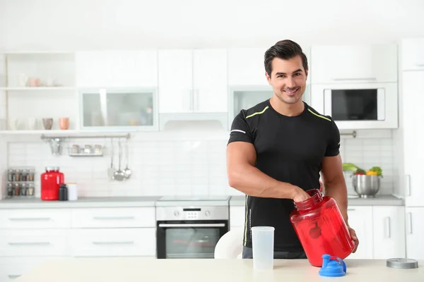 Jeune homme athlétique préparant une boisson protéinée dans la cuisine, espace pour le texte — Photo