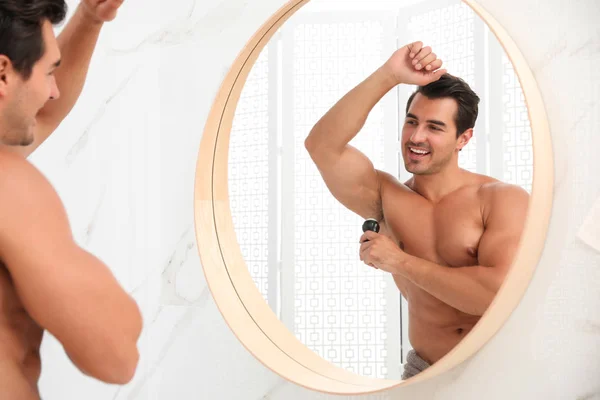Joven guapo aplicando desodorante en el baño — Foto de Stock