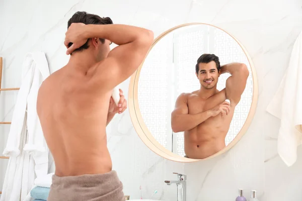 Bello giovane uomo che applica il deodorante in bagno — Foto Stock