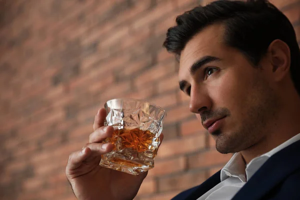 Kapalı kapılardaki tuğla duvarın yanında viski içlerinde viski içleriyle genç bir adam. Metin için alan — Stok fotoğraf