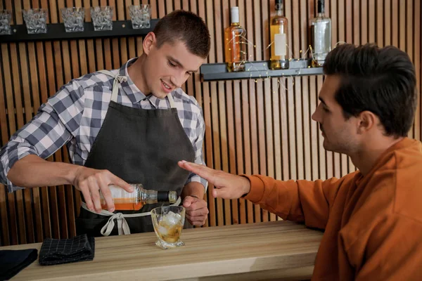 Bartender derramando uísque para o cliente no balcão no pub — Fotografia de Stock