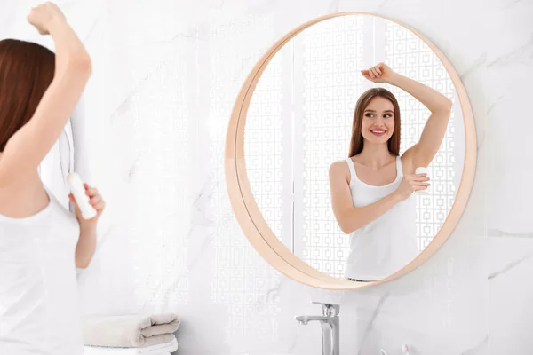 Krásná mladá žena aplikujícím deodorační přísada v koupelně — Stock fotografie