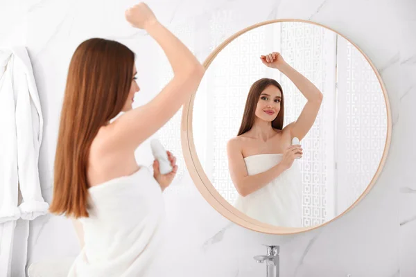 Hermosa mujer joven aplicando desodorante después de la ducha en el baño — Foto de Stock