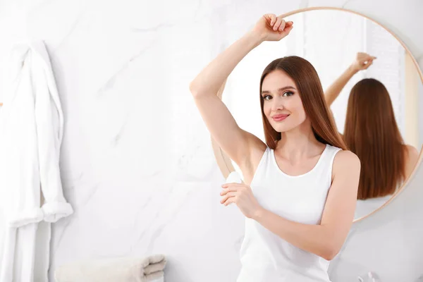 Vacker ung kvinna som ansöker deodorant i Bad rums. Utrymme för text — Stockfoto