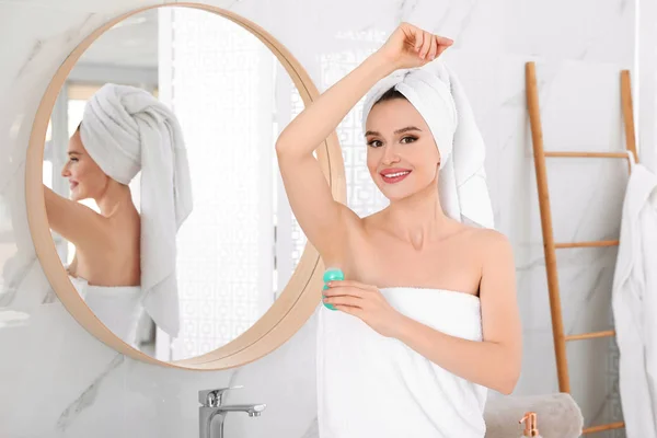 Hermosa mujer joven aplicando desodorante después de la ducha en el baño — Foto de Stock