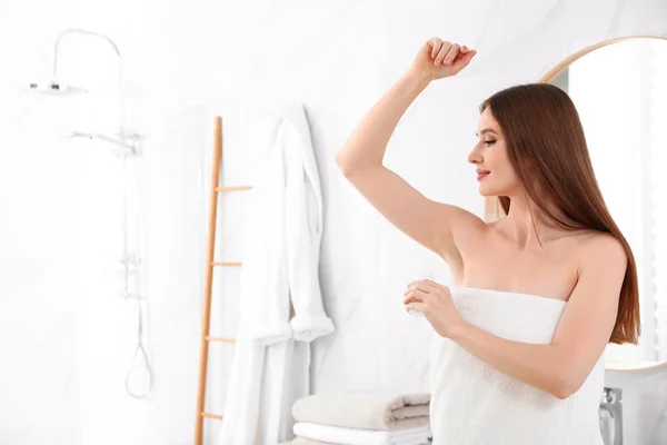 Belle jeune femme appliquant déodorant après la douche dans la salle de bain. Espace pour le texte — Photo