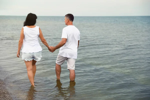 Gelukkig volwassen paar samen wandelen op zee strand. Ruimte voor tekst — Stockfoto