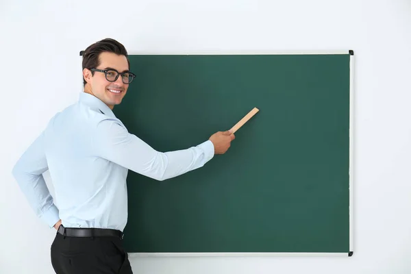 教室の黒板の近くに定規を持つ若い教師。テキスト用のスペース — ストック写真